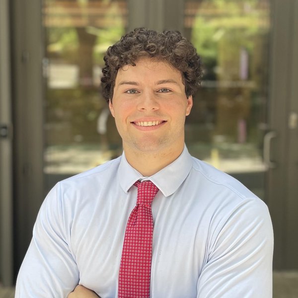 James Laprocido smiling in a collared shirt and red tie