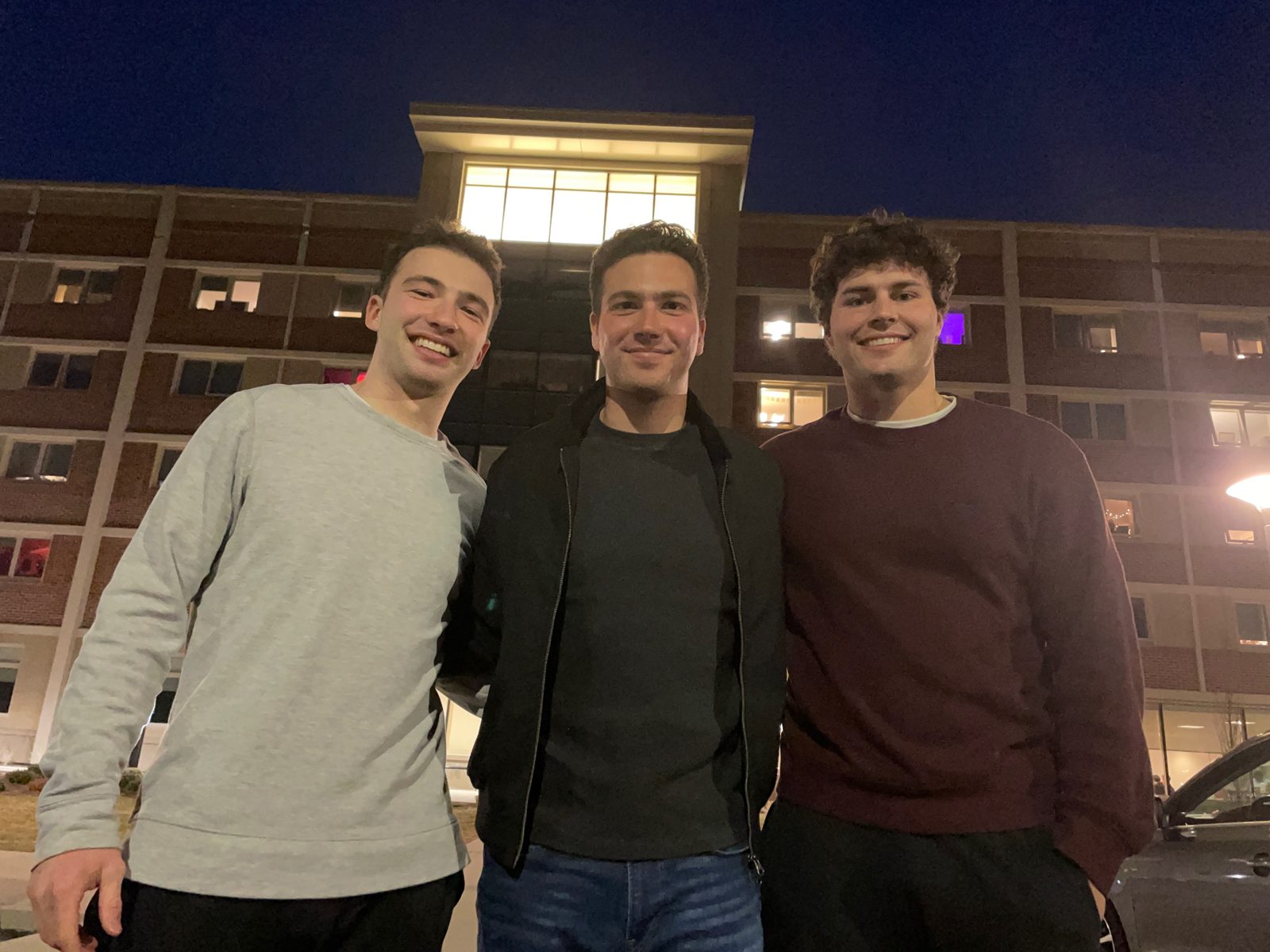 Three friends outside a building at night